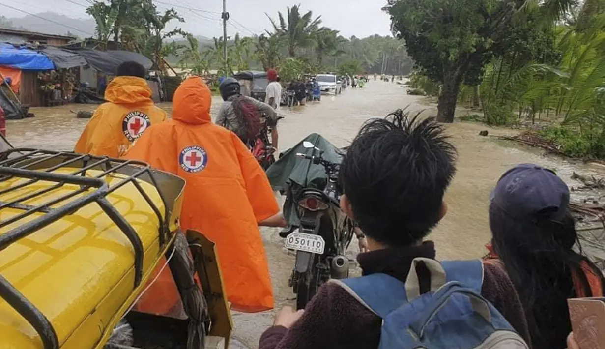 Palang Merah Filipina, relawan dan warga melintasi jalan yang banjir akibat topan Conson di desa Usab, provinsi Masbate, Filipina tengah (7/9/2021). (Philippine Red Cross via AP)