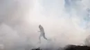 Seorang demonstran Palestina melarikan diri dari gas air mata yang ditembakkan oleh Israel selama protes terhadap permukiman Israel, di desa Tepi Barat Deir Jarir, utara Ramallah, Jumat (1/1/2021). (AP Photo/Majdi Mohammed)