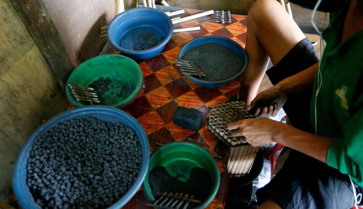 Pekerja memasukkan bubuk mesiu ke dalam sebuah tabung kecil saat membuat kembang api di sebuah gubuk, provinsi Bulacan, utara Manila, Rabu (27/12). Warga Filipina menyiapkan kembang api untuk menyambut tahun baru 2018. (AP/Bullit Marquez)