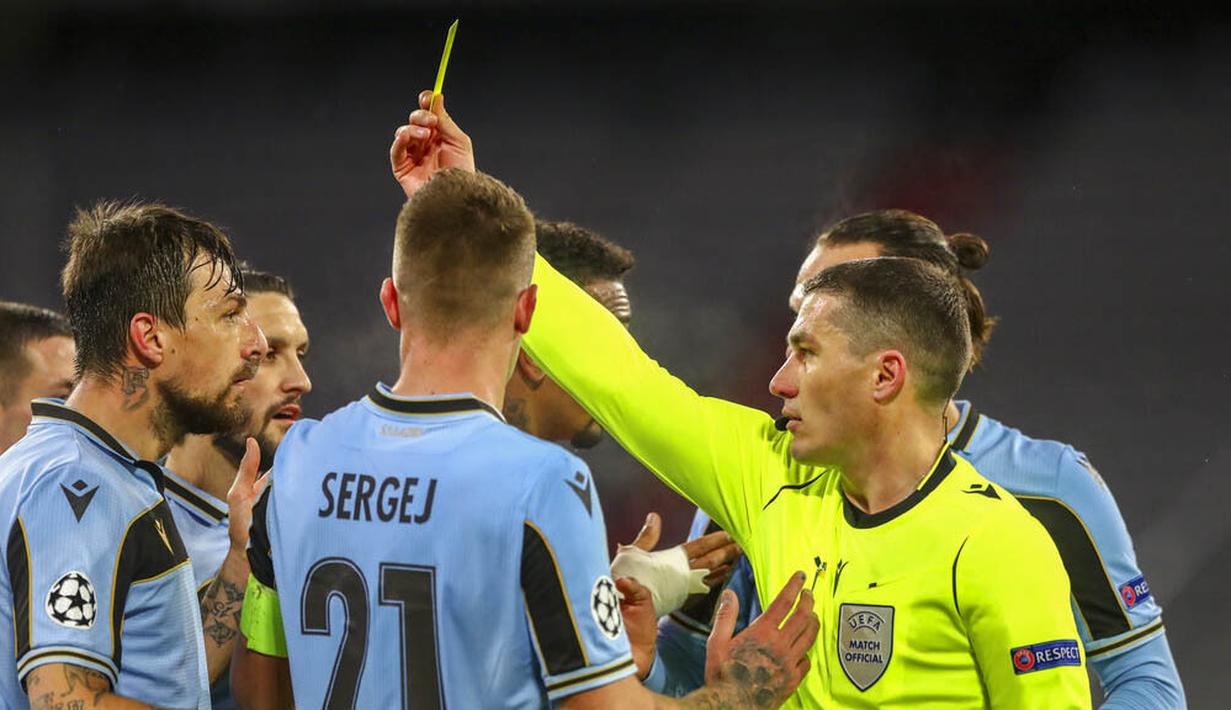 Wasit memberikan kartu kuning kepada pemain Lazio, Francesco Acerbi, saat melawan Bayern Munchen pada laga Liga Champions di Allianz Arena, Kamis (18/3/2021). Bayern Munchen menang dengan skor 2-1. (AP Photo/Matthias Schrader)