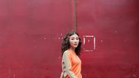 Sweater orange dipadu skinny jeans dan gaya rambut beach wave, buat tampilan lebih playful.