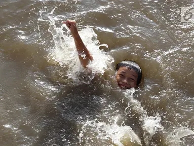 Seorang anak berenang di Kanal Banjir Barat, Jakarta, Jumat (23/3). Mahalnya biaya sewa kolam renang menyebabkan anak-anak berenang tidak pada tempatnya. (Liputan6.com/Immanuel Antonius)
