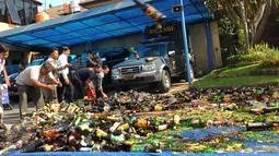 Sejumlah petugas saat melakukan pemusnahan miras di di Polres Kota Tangerang Banten, Rabu, (23/12). Polresta Tangerang memusnahkan miras sebanyak 11.155 botol dan 264 Ciu yang berkemas botol mineral. (Liputan6.com/Faisal R Syam)