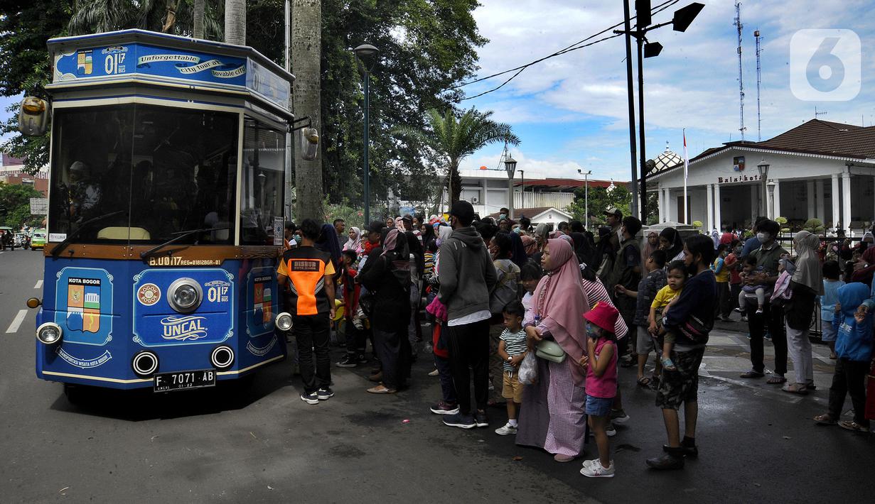 Warga antre masuk bus wisata Uncal di depan Balai Kota Bogor, Bogor, Jawa Barat, Minggu (29/5/2022). Bus wisata gratis yang disediakan untuk mengelilingi kawasan Kebun Raya Bogor setiap hari Sabtu dan Minggu ini mulai beroperasi kembali pascapandemi. (merdeka.com/Arie Basuki)