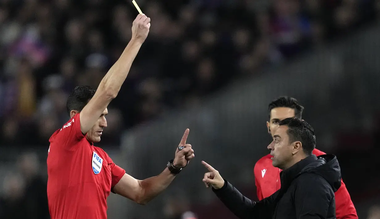 Wasit Juan Martinez Munuera memberikan kartu kuning kepada pelatih Barcelona, Xavi Hernandez saat menghadapi Real Madrid pada laga leg kedua semifinal Copa del Rey 2022/2023 di Camp Nou Stadium, Barcelona, Kamis (6/4/2023) dini hari WIB. (AP Photo/Joan Mateu Parra)