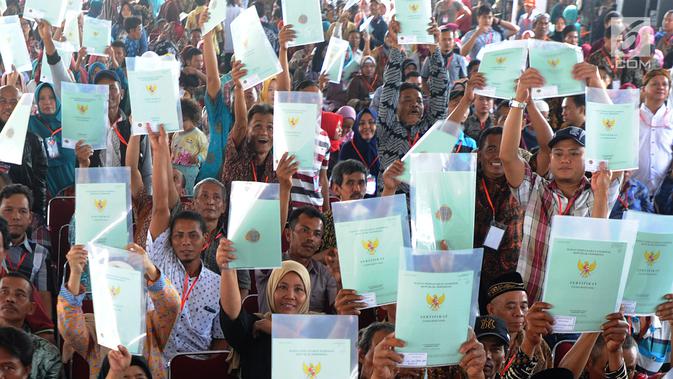 Warga menunjukkan sertifikat tanah saat mengikuti penyerahan sertifikat hak atas lahan tanah oleh Presiden Joko Widodo (Jokowi) di halaman depan Stadion Pakansari, Cibinong, Bogor, Selasa (25/9). (Merdeka.com/Arie Basuki)