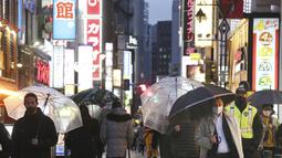 Orang-orang yang mengenakan masker untuk membantu melindungi diri dari penyebaran virus corona berjalan di sepanjang jalan yang dipenuhi bar dan restoran di Tokyo, Selasa (22/3/2022). Langkah-langkah pra-darurat untuk mencegah wabah Covid-19 telah dicabut. (AP Photo/Koji Sasahara)