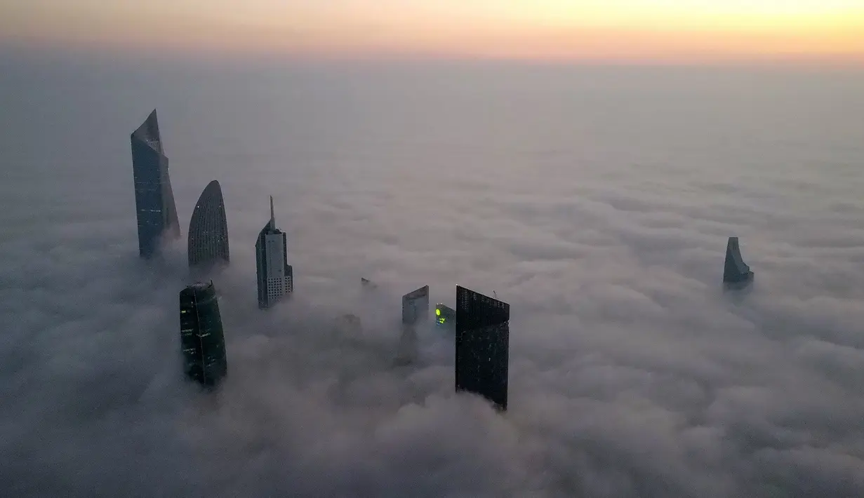 Foto udara memperlihatkan pemandangan gedung pencakar langit di tengah kabut tebal, Kuwait City, 21 Januari 2023. Kuwait memiliki gedung-gedung pencakar langit yang bahkan sampai menembus awan. (YASSER AL-ZAYYAT/AFP)