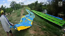 Warga membentangkan kain pantai untuk dijemur di bantaran sungai di Desa Mojolaban , Kabupaten Sukoharjo, Jawa Tengah, Rabu (25/10). Kain ini dijual dengan harga mulai dari Rp 15.000 hingga Rp 30.000 tergantung ukuran dan motif. (Liputan6.com/Gholib)