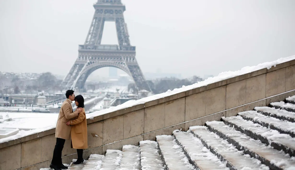 Pasangan berpose di depan Menara Eiffel di Paris, Prancis (7/2). Hujan salju yang sangat lebat membuat transportasi umum di paruh utara Prancis dan di Paris tidak dapat beroperasi. (AP Photo / Thibault Camus)