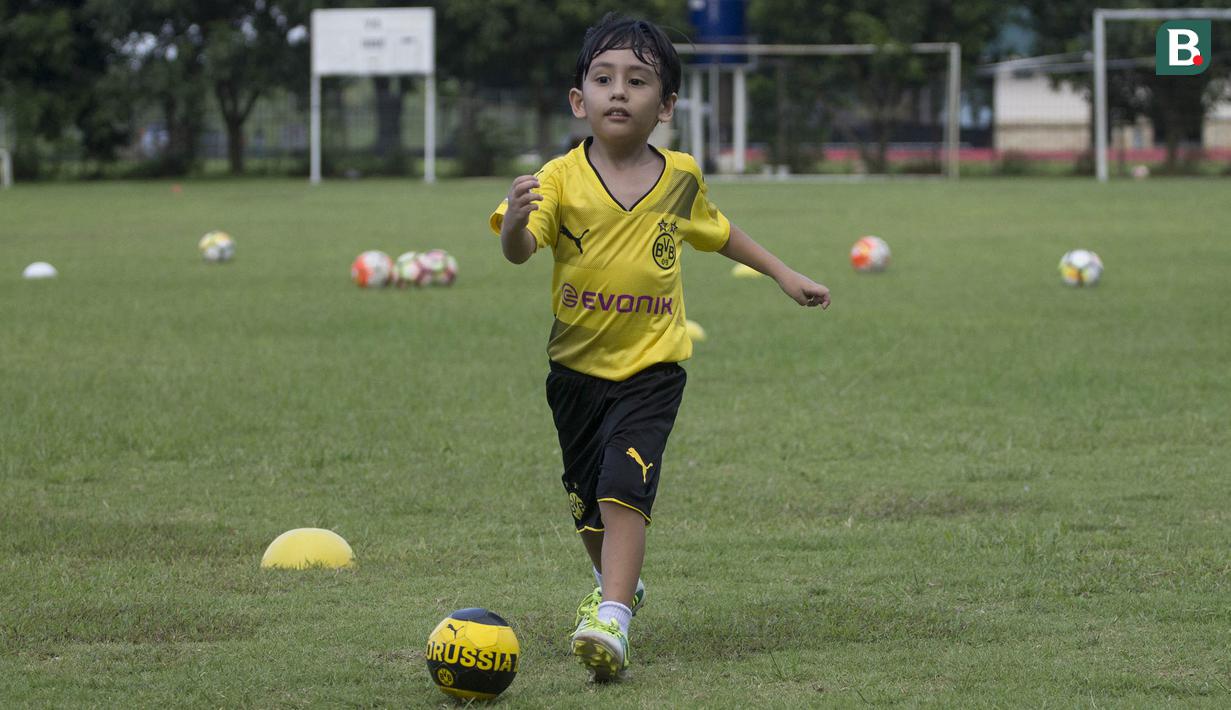 Anak dari Stefano Teco, yang bernama Romario, menggiring bola saat latihan Persija Jakarta di Lapangan Sutasoma, Jakarta, Minggu (25/2/2018). Ketika ayahnya bekerja sang anak asyik bermain sepak bola. (Bola.com/Aspirilla Dwi Adha)