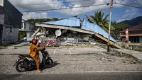 Sebuah sepeda motor berhenti di dekat bangunan yang runtuh pascagempa berkekuatan magnitudo 7,7 di Borong, Manggarai Timur, Nusa Tenggara Timur, Minggu, 16 Agustus 2026.. (AFP/ Juni Kriswanto)