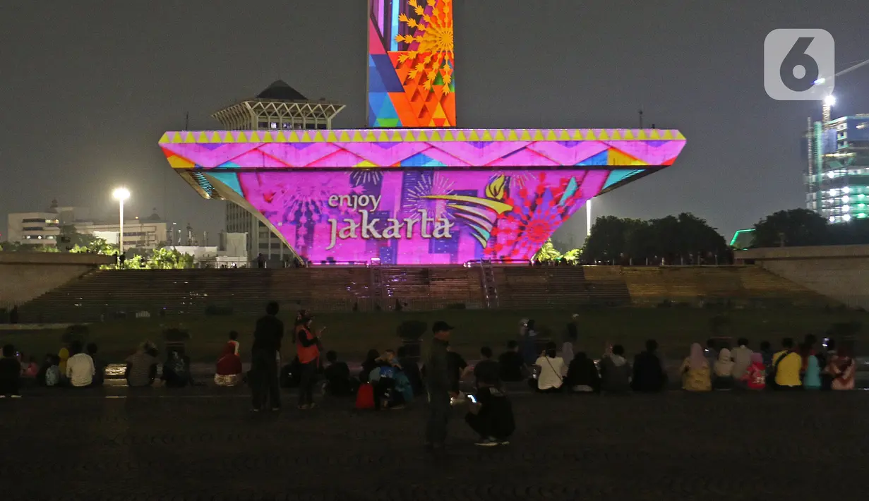Suasana saat warga menyaksikan pertunjukan video mapping di Monumen Nasional (Monas), Jakarta, Minggu (22/12/2019). Acara ini berlangsung di pelataran barat Tugu Monas pada 22-31 Desember 2019. (Liputan6.com/Herman Zakharia)