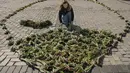 Seorang wanita menata bunga tulip di alun-alun Sophia di Kiev, Ukraina (18/3/2022). Warga Kiev turun ke alun-alun pusat untuk menata sekitar 1,5 juta bunga tulip bentuk lambang negara dalam pertunjukan normal yang menantang saat pasukan Rusia mengepung dan mengebom kota. (AP Photo/Vadim Ghirda)