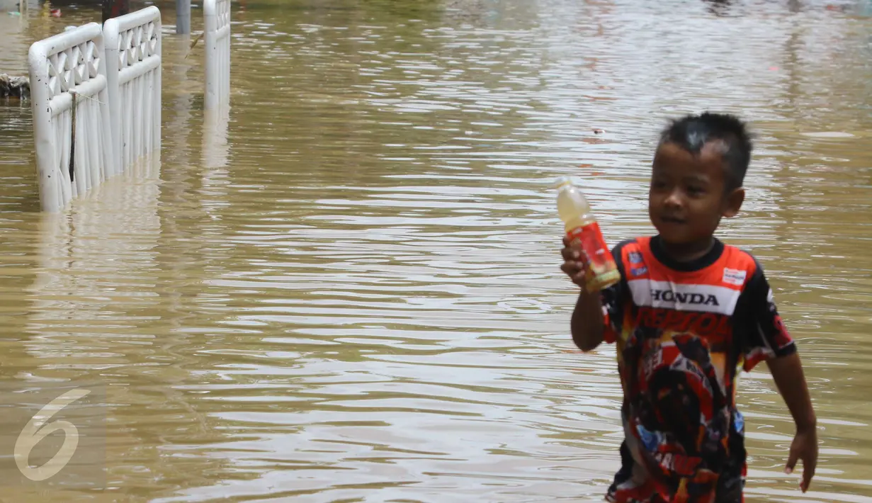 Seorang anak bermain di tengah jalan permukiman Bukit Duri, Jakarta yang terendam banjir, Kamis (16/2). Meluapnya Bendungan Katulampa, Bogor, menyebabkan permukiman kawasan Bukit Duri tergenang air dengan ketinggian 10 - 80 cm. (Liputan6.com/Helmi Afandi)