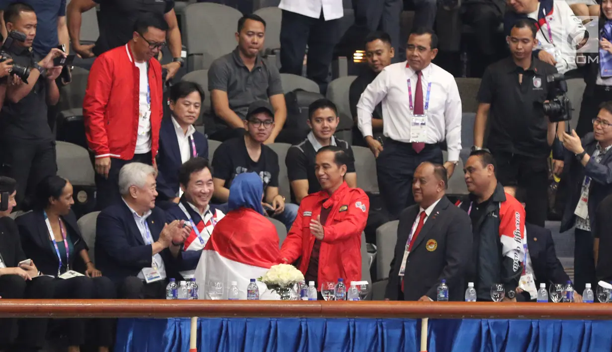 Atlet Taekwondo putri Indonesia, Defia Rosmaniar menyalami Presiden Joko Widodo usai merayakan kemenangan atas Salahshouri Marjan (Iran) pada Final Women Individual Poomsae di JCC, Jakarta, Minggu (19/8). (Liputan6.com/Helmi Fithriansyah)