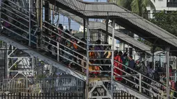 Penumpang menaiki jembatan penyeberangan setelah keluar dari kereta lokal pinggiran kota di Kolkata, India, Senin (1/11/2021). Layanan kereta api kembali normal setelah menerapkan pembatasan yang diberlakukan sebelumnya untuk mengekang penyebaran corona Covid-19. (DIBYANGSHU SARKAR/AFP)