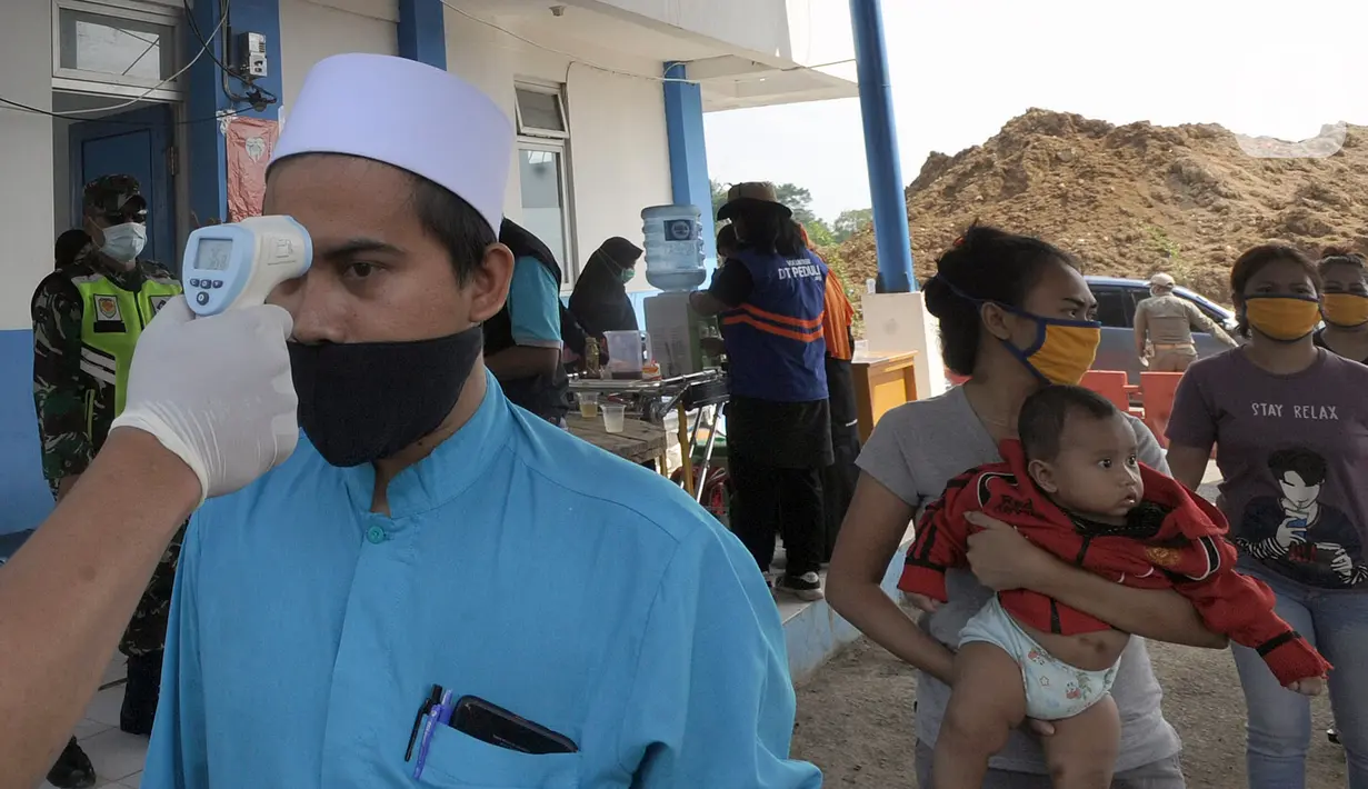 Petugas memeriksa suhu tubuh warga yang ingin menuju wilayah Sukabumi saat sterilisasi kendaraan di Terminal Cicurug, Sukabumi, Jawa Barat, Minggu (12/4/2020). Proses sterilisasi ini dilakukan untuk mencegah penyebaran virus corona COVID-19. (merdeka.com/Arie Basuki)
