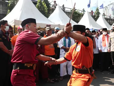 Dua warga beradu saat menampilkan pertunjukan kesenian bela diri asli Betawi Palang Pintu dalam Lebaran Tenabang 2022 di kawasan Tanah Abang, Jakarta, Sabtu (4/6/2022). Kegiatan yang menampilkan berbagai kesenian Betawi, makanan tradisional, perlombaan, dan bazar UMKM itu mengangkat tema KolaborAksi. (Liputan6.com/Angga Yuniar)
