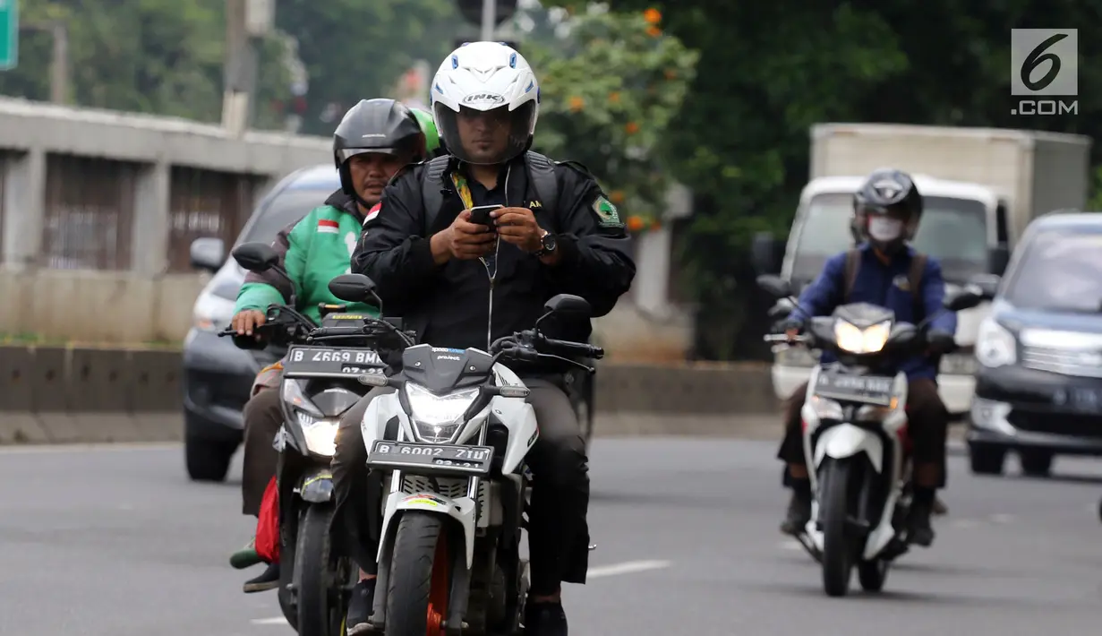 Pengendara mengoperasikan telepon seluler sambil mengendarai sepeda motor di Jalan Gatot Subroto, Jakarta, Kamis (8/3). Polisi menilai tindakan tersebut membahayakan karena  pengemudi menjadi tidak fokus di jalan raya. (Liputan6.com/Arya Manggala)