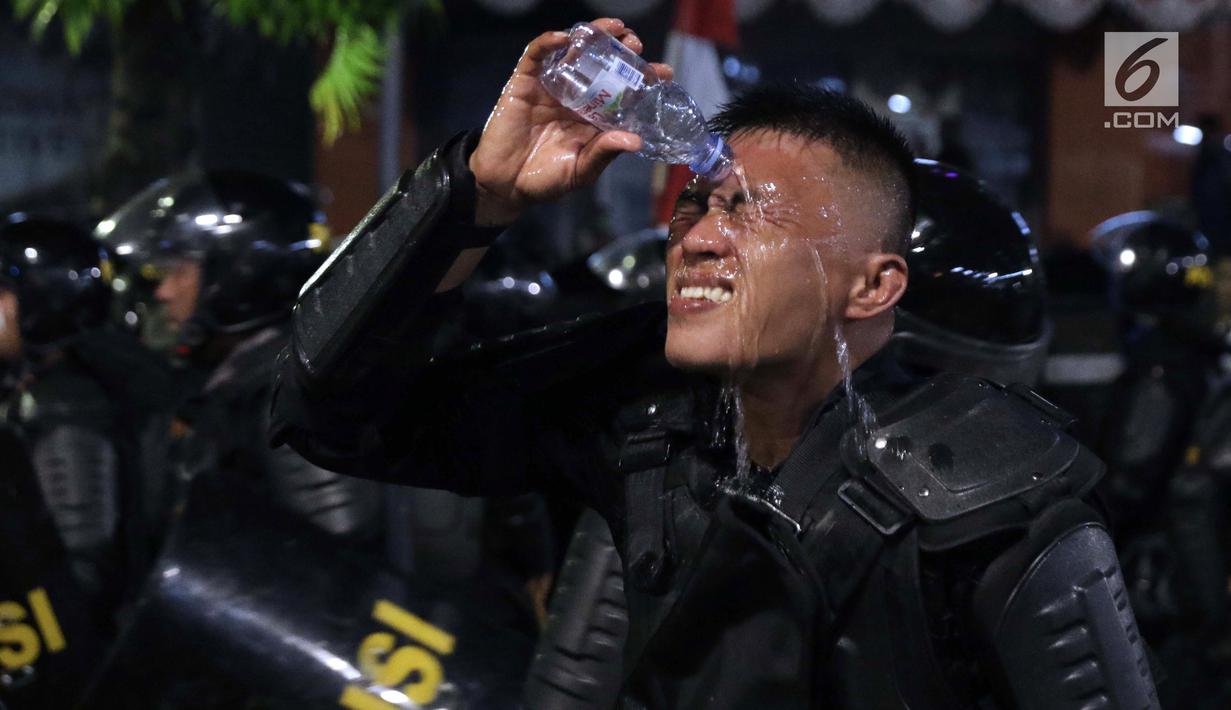 Personil Kepolisian dari satuan Brimob membasuh wajah di sela-sela tugas menghalaumassa yang berlakuanarkis di sekitardepanGedungBawaslu, Jalan MH Thamrin, Jakarta, Rabu (22/5/2019). Aksiunjuk rasa yang dimotori GNKR berakhirricuh. (Liputan6.com/HelmiFithriansyah)