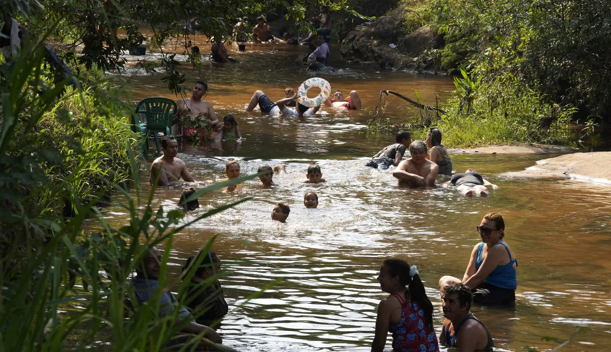 Orang-orang menyejukkan diri dari cuaca yang sangat terik di sungai saat gelombang panas di Paraguari, Paraguay, Minggu (16/1/2022). Suhu Paraguay secara umum mencapai 41 derajat celsius. (AP Photo/Jorge Saenz)