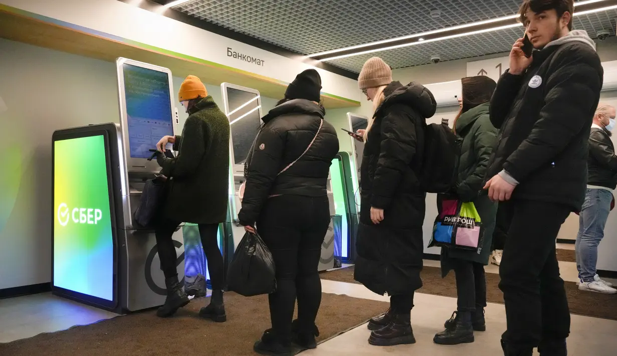 Orang-orang mengantre untuk menarik uang dari ATM di Sberbank di St. Petersburg, Rusia, 25 Februari 2022. Warga Rusia berbondong-bondong ke bank dan ATM tak lama setelah Rusia melancarkan serangan ke Ukraina dan Barat mengumumkan sanksi yang melumpuhkan ekonomi. (AP Photo/Dmitri Lovetsky)