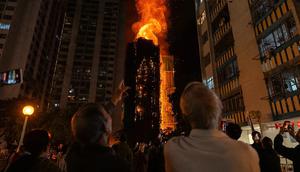 Orang-orang menyaksikan kebakaran hebat yang melalap sebuah gedung di Wang Fuk Court, sebuah kawasan hunian di Distrik Tai Po, New Territories, Hong Kong, Rabu (26/11/2025). (Dok. AP/Chan Long Hei)