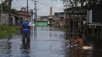 Seorang anak laki-laki menggunakan pintu lemari es untuk mengapung di seberang jalan yang dibanjiri oleh naiknya sungai Negro di Iranduba, negara bagian Amazonas, Brasil, Senin (23/5/2022). Wilayah Amazon sedang dilanda banjir dengan 35 kotamadya yang menghadapi salah satu banjir terburuk mereka dalam beberapa tahun dan permukaan air diperkirakan akan meningkat selama beberapa bulan mendatang. (AP Photo/Edmar Barros)