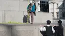 Polisi saat akan menangkap dua aktivis Greenpeace yang memasangkan masker pada sejumlah patung bersejarah di pusat kota London, Inggris, Senin (18/4). Aksi unik itu dilakukan untuk memprotes kualitas polusi udara di kawasan tersebut. (Leon NEAL/AFP)