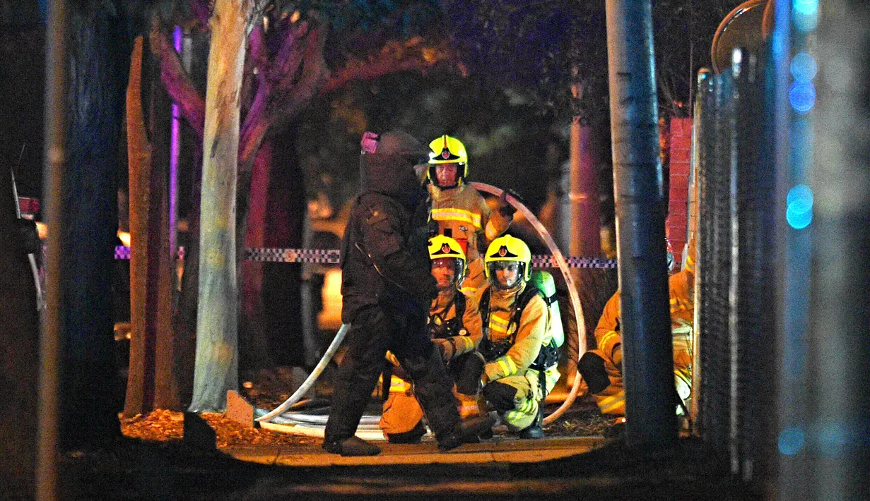 Tim gegana mengenakan pakaian pelindung setelah seorang pria yang mengendarai mobil berisi tabung gas dan menabrak pintu gerbang markas polisi Merrylands, Sydney Barat, Kamis (21/7). Pria itu sebelumnya mengklaim membawa bom. (AAP/Sam Mooy via REUTERS)