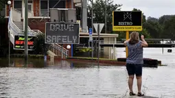 Seorang warga mengambil gambar meningkatnya air banjir akibat hujan deras di pinggiran barat daya Camden, Sydney, Australia, Selasa (8/3/2022). (Muhammad FAROOQ/AFP)