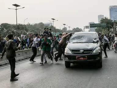 Massa aksi  melakukan penyerangan terhadap mobil pelat nomor merah yang melintasi jalan tol seberang Gedung DPR/ MPR RI, Jakarta, Selasa (24/9/2019). Selain menutup ruas tol, kendaraan dinas pemerintah dan milik polisi jadi korban pelemparan dan perusakan oleh mahasiswa. (Liputan6.com/Faizal Fanani)