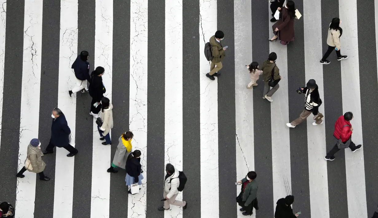 Orang-orang berjalan di sepanjang penyeberangan pejalan kaki di Tokyo (18/1/2022). Pemerintah Jepang sedang mempersiapkan pembatasan sosial di Tokyo dan wilayah lain karena varian omicron dari virus corona menginfeksi lebih banyak orang. (AP Photo/Eugene Hoshiko)