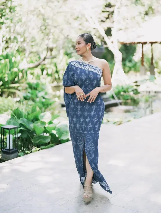 Tidak hanya itu, dalam potret lainnya, Happy Salma tampil memukau dalam balutan one-shoulder dress wastra berwarna biru dengan detail high-slit yang menambah kesan elegan sekaligus berani. Penampilannya semakin sempurna dengan aksesori perhiasan emas yang ia kenakan, menonjolkan sisi feminim namun tetap modern. [@happysalma].