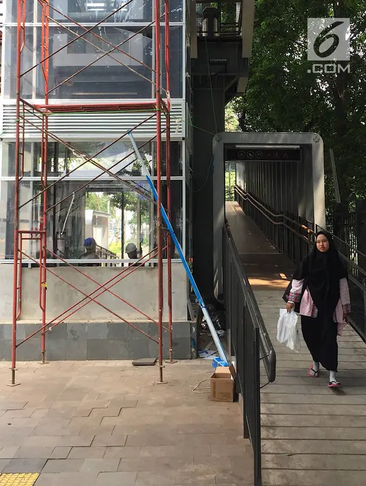 Pejalan kaki melintas di dekat pembangunan lift pada jembatan penyeberangan orang di Jakarta, Senin (13/5). Pembangunan lift pada tiga JPO yang berada di Jalan Sudirman itu bertujuan meningkatkan kenyamanan kepada warga dan ditargetkan rampung akhir bulan ini.(Liputan6.com/Immanuel Antonius)