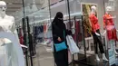 Seorang wanita yang mengenakan niqab meninggalkan toko pakaian setelah berbelanja di Istanbul, Turki, 13 Agustus 2018. Para turis dari negara-negara Arab rela antre hingga ke luar toko demi mendapatkan barang bermerk dengan harga murah. (AFP/Yasin AKGUL)
