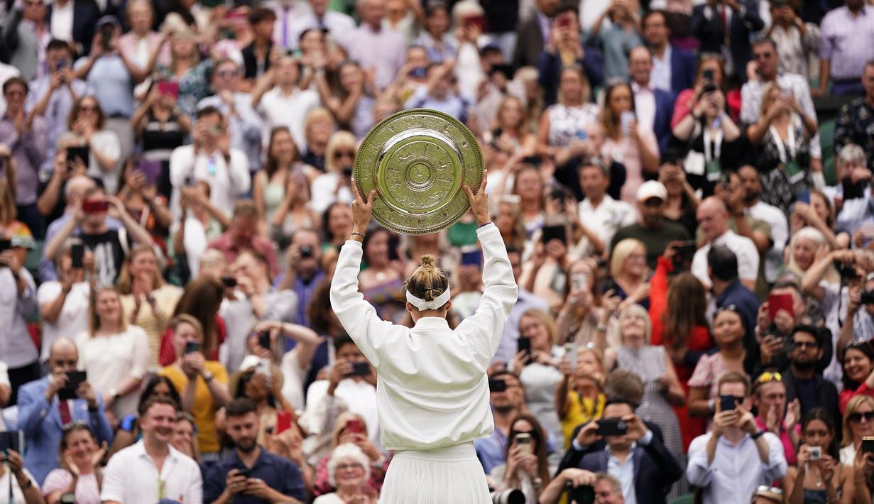 Selebrasi petenis tunggal putri Republik Ceska, Marketa Vondrousova dengan mengangkat trofi juara di hadapan penonton setelah mengalahkan petenis Tunisia, Ons Jabeur pada laga final turnamen tenis Wimbledon 2023 di All England Lawn and Tennis Club, London, Sabtu (16/7/2023) malam WIB. (AP Photo/Alberto Pezzali)