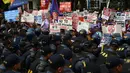 Polisi anti huru-hara berjaga saat unjuk rasa di depan kedutaan AS, Manila, Filipina (20/1). Ratusan warga Filipina berunjuk rasa jelang pelantikan Presiden terpilih AS, Donald Trump. (AFP Photo/Ted Aljibe)