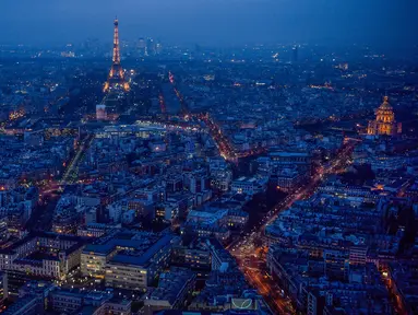 Pemandangan kota Paris saat sore hari dari atap gedung pencakar langit "The Tour Montparnasse", memperlihatkan Menara Eiffel dan kubah Hotel Les Invalides (kanan), Senin (8/1). Paris terkenal dengan keindahan di setiap sudutnya. (CHRISTOPHE SIMON/AFP)