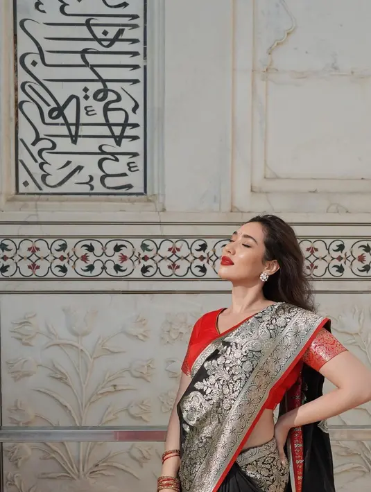 Memadukan atasan merah dengan kain sari hitam gold yang tampilkan pesona lain dari Laksmi. [@laksmideneefe]