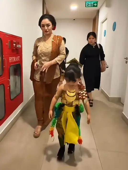 Melengkapi tampilannya dengan selendang batik coklat yang dihiasi bros rantai emas. Dipadukan bawahan kain lilit batik coklat serta heels sandal warna senada.  [@sitibadriahh]