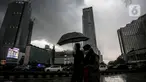 Warga menggunakan payung melintas di kawasan Bundaran Hi, Jakarta, Sabtu (13/11/2021). Badan Meteorologi Klimatologi dan Geofisika (BMKG) melansir peringatan terbaru yang berlaku 7-9 November 2021 soal peringatan cuaca ekstrem imbas dari La Nina. (Liputan6.com/Faizal Fanani)