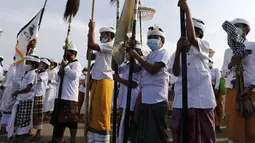 Anak-anak mencelupkan kaki ke laut saat mengikuti ritual Melasti di Bali, Senin (28/2/2022). Ritual yang dilakukan menjelang Hari Raya Nyepi umat Hindu ini diadakan untuk menyucikan alam semesta dari pengaruh buruk, perbuatan dan pikiran buruk. (AP Photo/Firdia Lisnawati)