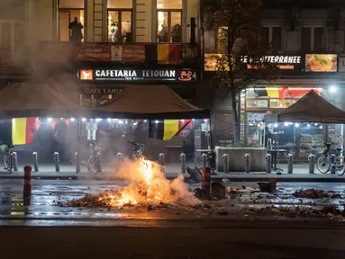 Kebakaran terlihat di depan bar selama bentrokan setelah timnas Maroko kalah dari Prancis pada laga semifinal Piala Dunia 2022, di Brussel, Belgia, Rabu (14/12/2022). Penggemar bola di Brussel terlibat bentrok seusai laga Prancis vs Maroko selesai. (Simon Wohlfahrt / AFP)
