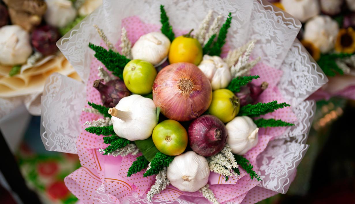 Seorang pekerja membuat karangan bunga yang terbuat dari bawang merah, tomat, dan bawang putih di pasar bunga di Manila, Filipina, Senin (13/2/2023). Buket tersebut merupakan bagian dari gimmick Hari Kasih Sayang oleh seorang pemilik toko bunga yang mengatakan lebih praktis daripada memberi bunga karena Anda bisa memasaknya setelah itu. (AP Photo/Aaron Favila)