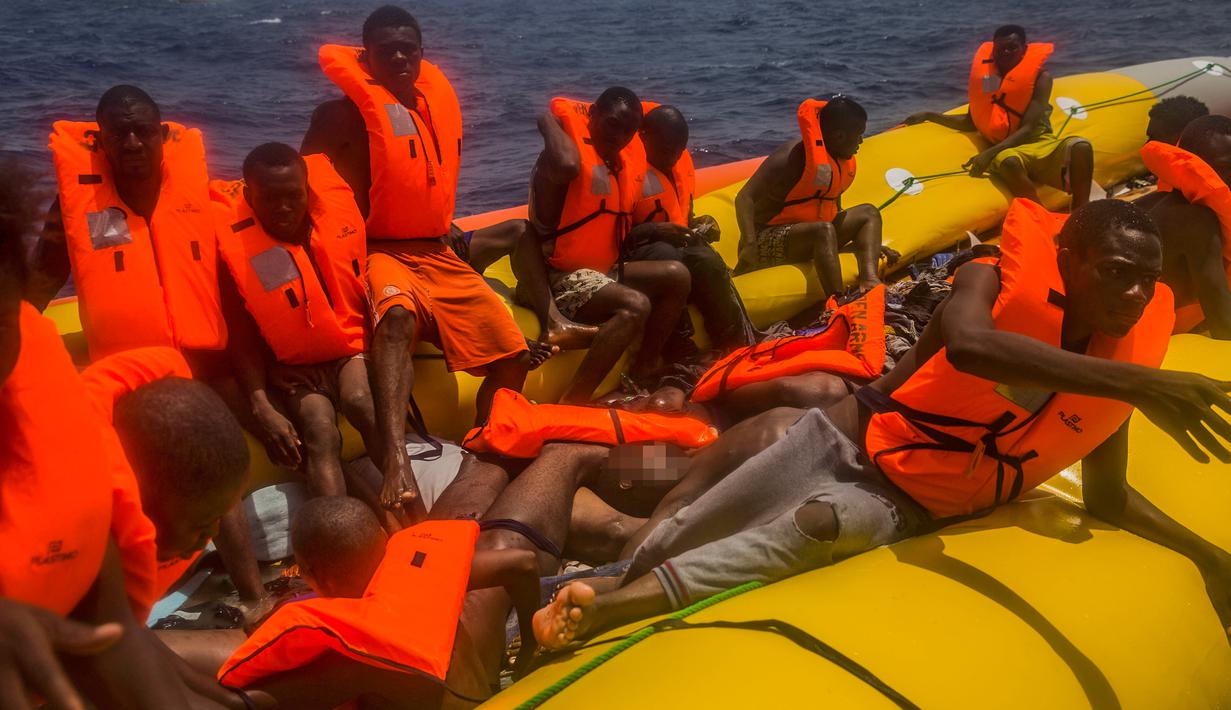Sejumlah imigran menunggu di atas perahu karet untuk diselamatkan di lepas pantai Libya, Selasa (25/7). Kapal penyelamat kemanusiaan milik LSM asal Spanyol, Proactiva Open Arms, menemukan 13 jasad di atas perahu karet tersebut. (AP/Santi Palacios)