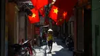 Warga berjalan di sepanjang gang yang dihiasi bendera nasional Vietnam menjelang perayaan Hari Nasional Vietnam di Hanoi (1/9/2020). Peringatan 75 tahun Hari Nasional Vietnam jatuh pada tanggal 2 September 2020. (AFP Photo/Nhac Nguyen)
