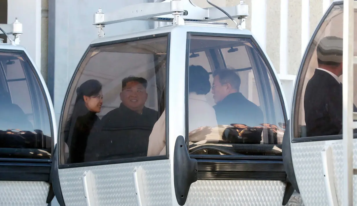 Presiden Korea Selatan Moon Jae-in beserta istri Kim Jung-sook dan Pemimpin Korea Utara Kim Jong-un beserta istri Ri Sol-ju naik kereta gantung di Gunung Paektu, Korea Utara, Kamis (20/9). (Pyongyang Press Corps Pool via AP)
