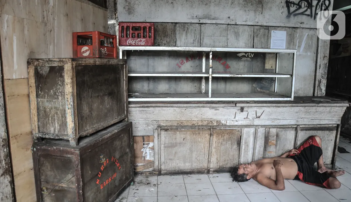 Seorang warga saat tidur di depan salah satu kios yang tutup di Blok G Pasar Tanah Abang, Jakarta, Rabu (30/11/2022). Ketua Komisi B DPRD DKI Jakarta Ismail pun pada Oktober 2022 menyarankan Perumda Pasar Jaya membentuk tim untuk mengawal proses pendataan pedagang untuk mendapat Tempat Penampungan Sementara (TPS) hingga terealisasinya proses revitalisasi pasar pada 2023. (merdeka.com/Iqbal S. Nugroho)